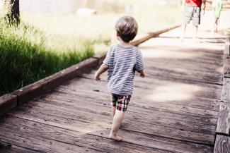 Boy running on wooden bridge.